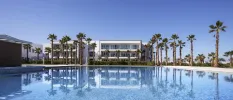 White building overlooking a large swimming pool and palm trees