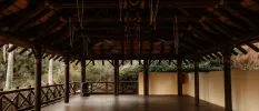 Open-sided pavilion with a wooden ceiling and floors and a view of tropical gardens