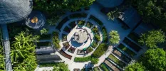 Aerial view of thatched villas and plant beds in a circular design, with a table at the centre