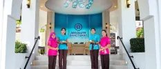 Smiling staff in pink and blue uniforms stand on the steps at the entrance to Absolute Sanctary, with contemporary hanging blue lights overhead