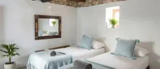 Twin beds dressed in white and powder blue, a cobbled stone ceiling an wooden wall mirror