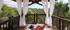 Wooden terrace with white drapes, a mattress, pillow and yoga mat with tropical forest surrounds