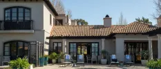 Terracotta-roofed villa with a private pool, surrounded by blue potted plants, and grey loungers with blue and white striped towels