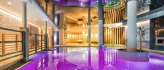 Indoor pool with purple lights, white pillars and black and white retro images of women on the beach