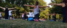 Group participating in an outdoor fitness session with outstretched arms