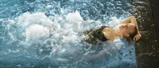 Woman relaxing in a swimming pool with under-water jets