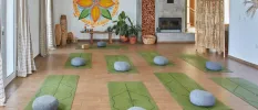 Studio with green yoga mats and blue round cushions laid out for a group session