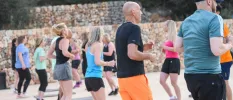 Men and women in active wear take part in a fitness class in a stone outdoor courtyard