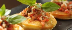Crusty crostini topped with chopped tomatoes and a sprig of basil
