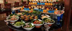 Buffet table set up, with glasses of blue and orange liquid, and bowls of salad and grains