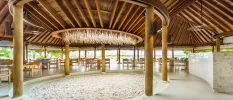 Open-sided pavilion with wood-beamed ceilings, a central pit of white decorative stones and tables and chairs
