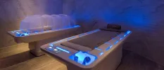 Two futuristic looking treatment beds with blue lighting in a dark spa cabin