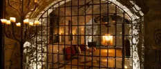 Black prison-style railings in front of a candlelit room with patterned cushions 
