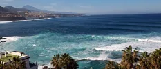 Palm trees, seawater pool and the Atlantic Ocean with mountains in the foreground
