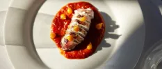 Lobster on a bed of tomato-like puree on a white plate