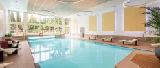 Large indoor swimming pool with floor to ceiling windows overlooking hotel's gardens. 