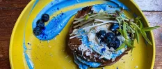 Yellow plate topped with healthy looking food including blueberries and herbs