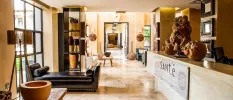 SANté Wellness Retreat & Spa entrance lobby, with a brown leather sofa, neutral floors and walls, and sculptures made from warm wood