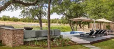 Stone terrace with a pool, loungers and parasols overlooking reserve greenery