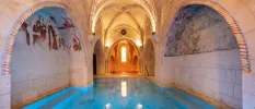 Indoor swimming pool in a room with vaulted stone ceilings and frescoes