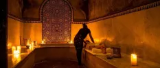 Person lying down in a hammam enjoying a massage surrounded by candlelight