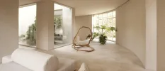 Stylish, neutral room with a plant, large windows and cushioned seating areas