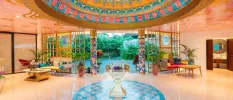 Lobby area with intricate blue floor tiles, sofas with colourful cushions and an intricately painted ceiling dome in multiple colours