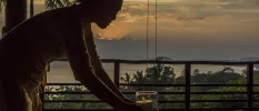 Staff member lights a candle on a table in an open-air pavilion with a sea view