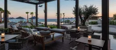 Lantern-lit outdoor seating area with tables and cushioned chairs overlooking the ocean at dusk