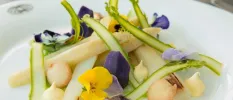 Plate of vegetables garnished with purple and yellow edible flowers