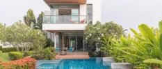 Angular two-storey villa with a glass-fronted balcony, swimming pool and gardens