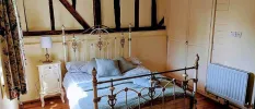 Traditional cosy bedroom with wooden beams and wrought-iron bed