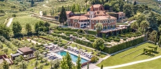 Six Senses Douro Valley exterior, a historic manor house with a swimming pool and leafy terraced vineyard surrounds