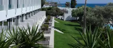 A row for furnished terraces with steps leading down to a lawned garden with the sea in the background