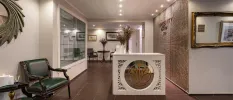 Entrance room with tiled walls, gold mirrors, vases of flowers and tiled floors