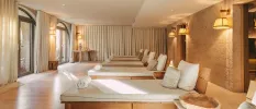 Chic relaxation room with wooden white-cushioned loungers, neutral curtains and soft lighting