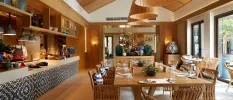 Stylish dining area with a wooden table, rattan lantern-style ceiling lights, and a show cooking station with chefs hard at work