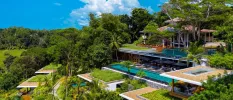 Resort staggered on a hillside shrouded in jungle greenery, with swimming pools and blue cushioned daybeds