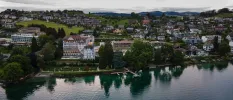 Chenot Palace from the lakefront, fronted by greenery and a wooden jetty