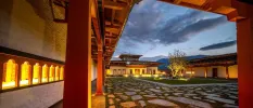 Cobbled courtyard in a monastery at twilight, as warm light pours from the inside