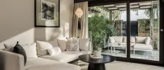 Stylish villa living area, with a white sofa, black coffee table and patio doors that showcase an outdoor sofa and table in a walled courtyard