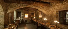 Restaurant with stone walls and ceilings, wooden beans and tables laid up, lit by candlelight