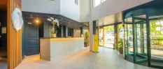 Modern reception area with revolving doors, tiled floors, and a desk with spotlights and a huge potted plant