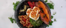 Dark bowl with sweet potato and seeds, chick peas, halloumi and avocados and tomatoes