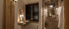Stone shower area with white curtain and desk next to a small dark-wood window