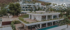 Tiered white building showing swimming pool, gardens and lawn with mountains in the background