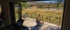 Man works out on a wooden deck with views of the African greenery and river