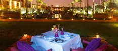 Dinner table set up after dark with candles and a view of landscaped grounds