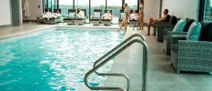Indoor swimming pool with surrounding wicker chairs and guests in robes