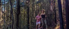 Couple jog through a leafy forest in trainers and active wear